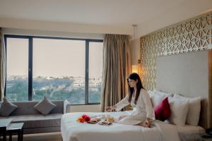 a woman sitting on a bed in a hotel room at Ramada by Wyndham Jaipur North in Jaipur