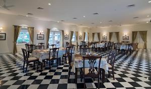 a restaurant with tables and chairs on a checkered floor at Tree of Life Sariska, Manor in Tehla