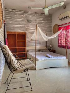 um quarto com uma cama, uma rede de descanso e uma cadeira em La Guesthouse Étoile em Cotonou