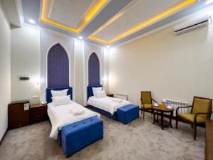 a hotel room with two beds and a table and chairs at Marakanda Hotel Samarkand in Samarkand