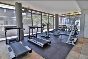 a gym with treadmills and machines in a room with windows at Infinity LG3 Seaview Beach Apartment in Cape Town