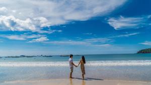 Ein Mann und eine Frau, die am Strand Händchen hält. in der Unterkunft Panja Resort Palawan in Puerto Princesa