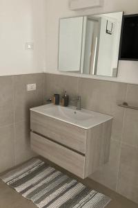 a bathroom with a sink and a mirror and a rug at Appartamento AnnaChiara in Arco