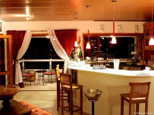a kitchen and living room with a bar and chairs at Hospedaria Fascino Del Mare Guesthouse in Ilhabela