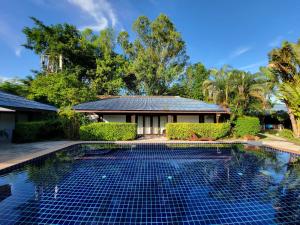 a swimming pool in front of a house at Satva Samui Yoga and Wellness Resort in Amphoe Koksamui
