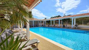 a swimming pool with chairs and a house at Hotel et Spa Les Cleunes Oléron in Saint-Trojan-les-Bains