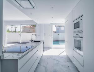 a white kitchen with a pool in the background at Villa Fresno with Private Pool on gated 5* Mar Menor Golf Resort - 3 Bed/3 shower/WC in Torre-Pacheco