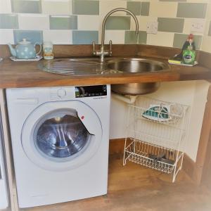 a kitchen with a sink and a washing machine at Meg's Cottage in Taunton