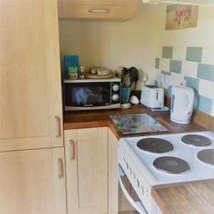a kitchen with a microwave and a stove top oven at Meg's Cottage in Taunton