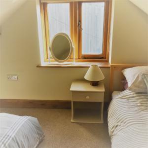 una camera da letto con specchio, letto e finestra di Meg's Cottage a Taunton