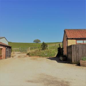 einen Feldweg neben einer Scheune und einem Zaun in der Unterkunft Meg's Cottage in Taunton