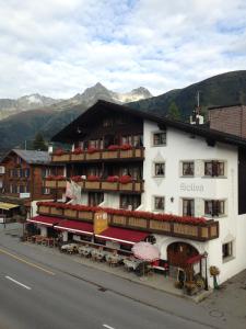 a large white building with red awnings on a street at Hotel Soliva in Sedrun