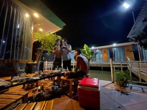 Xu xu motel في Bạc Liêu: مجموعة من الرجال واقفين على شرفة في الليل