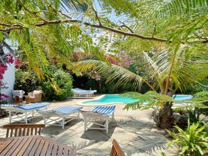 un patio con tumbonas y una piscina en HUHURU House en Watamu