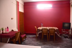 a dining room with a table and a red wall at J&B Homestay in Dibrugarh