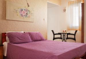 a bedroom with a purple bed and a table with chairs at City Center Apartments in Haifa