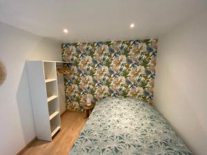 - une chambre avec un lit et un papier peint floral dans l'établissement L’Albâtre - Maison située à quelques pas de la mer, à Saint-Aubin-sur-Scie
