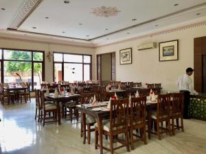 a restaurant with tables and chairs and a man standing in a room at The Birder's Inn in Bharatpur