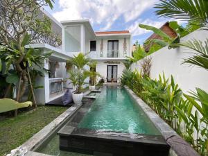 a swimming pool in front of a house at Villa Kalma Canggu in Canggu