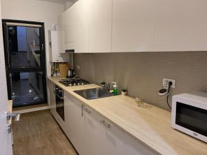 a kitchen with white cabinets and a sink and a microwave at Energy Luxury Apartment Near Presidential Palace in Bucharest