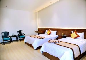 a hotel room with two beds and two chairs at Khách Sạn LUCIEN HOTEL Quy Nhơn in Quy Nhon