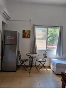 Zimmer mit einem Tisch, Stühlen und einem Kühlschrank in der Unterkunft City Center Apartments in Haifa