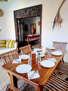 een houten tafel met borden en servetten erop bij HUHURU House in Watamu