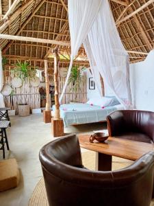 a bedroom with a bed and a table and a chair at HUHURU House in Watamu