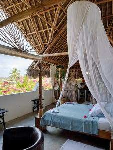 a bedroom with a bed with a mosquito net at HUHURU House in Watamu
