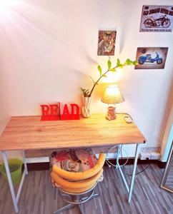 a wooden table with a lamp and a chair under it at Newnormal Hotel in Chiang Mai