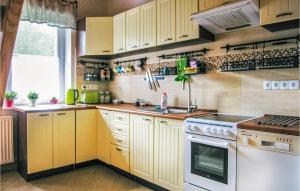 a kitchen with yellow cabinets and a white stove top oven at 2 Bedroom Nice Home In Szemud in Rąb