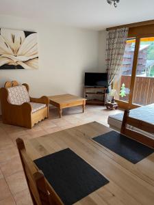 ein Wohnzimmer mit einem Sofa, einem Stuhl und einem TV in der Unterkunft Studio , Val-d’Illiez in Val dʼIlliez