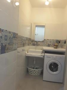 y baño con lavadora y espejo. en A casa dei 3, en Catania