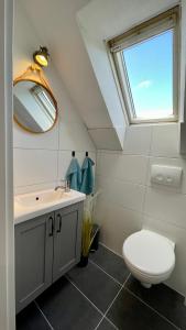 ein Bad mit einem WC, einem Waschbecken und einem Fenster in der Unterkunft Gemütliches Landhaus in Harmsdorf in Harmsdorf