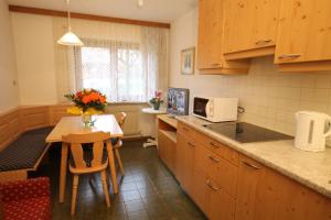 una cocina con armarios de madera y una mesa con sillas. en Residence Ben Ste, en Ortisei