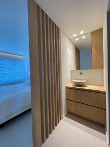 a bedroom with a bed and a sink and a mirror at Zeedijk Oostduinkerke frontaal zeezicht - volledig gerenoveerd 2022! in Oostduinkerke