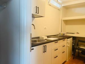 una cucina con armadi bianchi e lavandino di Oderisi Studio Suite a Roma Altre 6 foto
