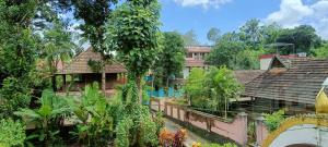 a group of houses with trees and plants at Swasthi Griha in Aranmūla
