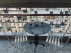 a table with two cups and two chairs on a balcony at Athens Sunnyside condo in Athens