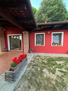 a red house with red flowers in a yard at B&B Cascina Bedria in Ivrea