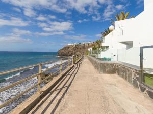 einen Fußweg zum Strand neben einem weißen Gebäude in der Unterkunft Viewpoint Over The Cliff By CanariasGetaway in Maspalomas