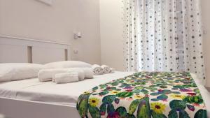 a white bedroom with a bed with a floral blanket at Marricrio House in Catania