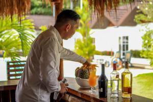 Un uomo in piedi a un tavolo con un drink di Sunz en Coron Resort a Coron