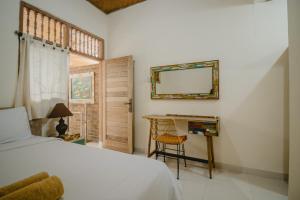 a bedroom with a bed and a desk and a mirror at Samblung Mas House in Denpasar