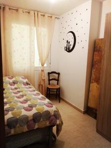 um quarto com uma cama com um edredão e uma cadeira em Estupendo piso en L'AMPOLLA em L'Ampolla