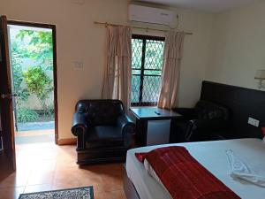 ポカラにあるPokhara Cottageのベッドルーム1室(ベッド1台、椅子、窓付)