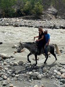 two people riding a horse through a river at Lento Kaldani Guesthouse in Adishi