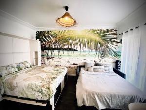1 dormitorio con 2 camas y un mural de palmeras en Baie-Des-Anges Studio Front de Mer, en Villeneuve-Loubet