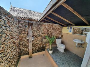 a bathroom with a toilet and a stone wall at Scuba Republic Beach Bungalows in Bira