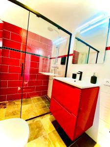 baño rojo con lavabo y ducha en Baie-Des-Anges Studio Front de Mer, en Villeneuve-Loubet